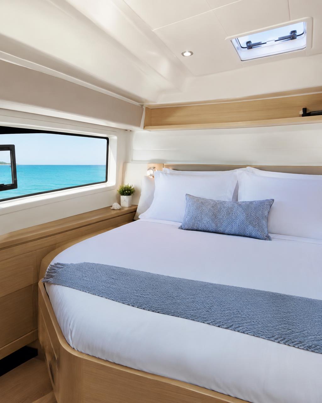 A bright double cabin with crisp linens and a hull window looking out to sea